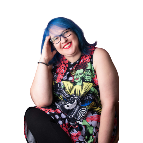 woman with blue hair and glasses smiling at the camera wearing a bright coloured dress 